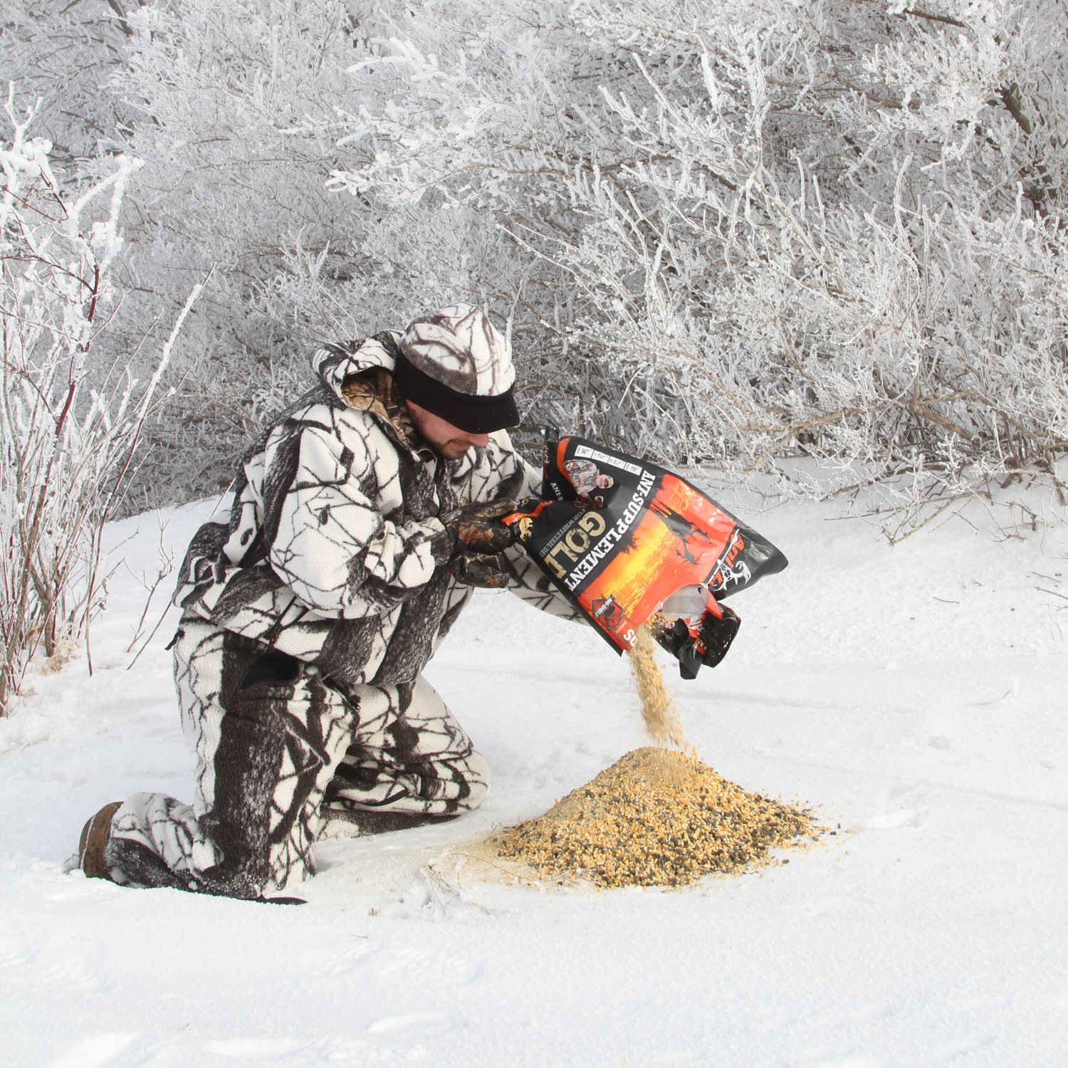 Man pouring out a bag of Ani-Supplement Gold onto the ground that's covered with snow