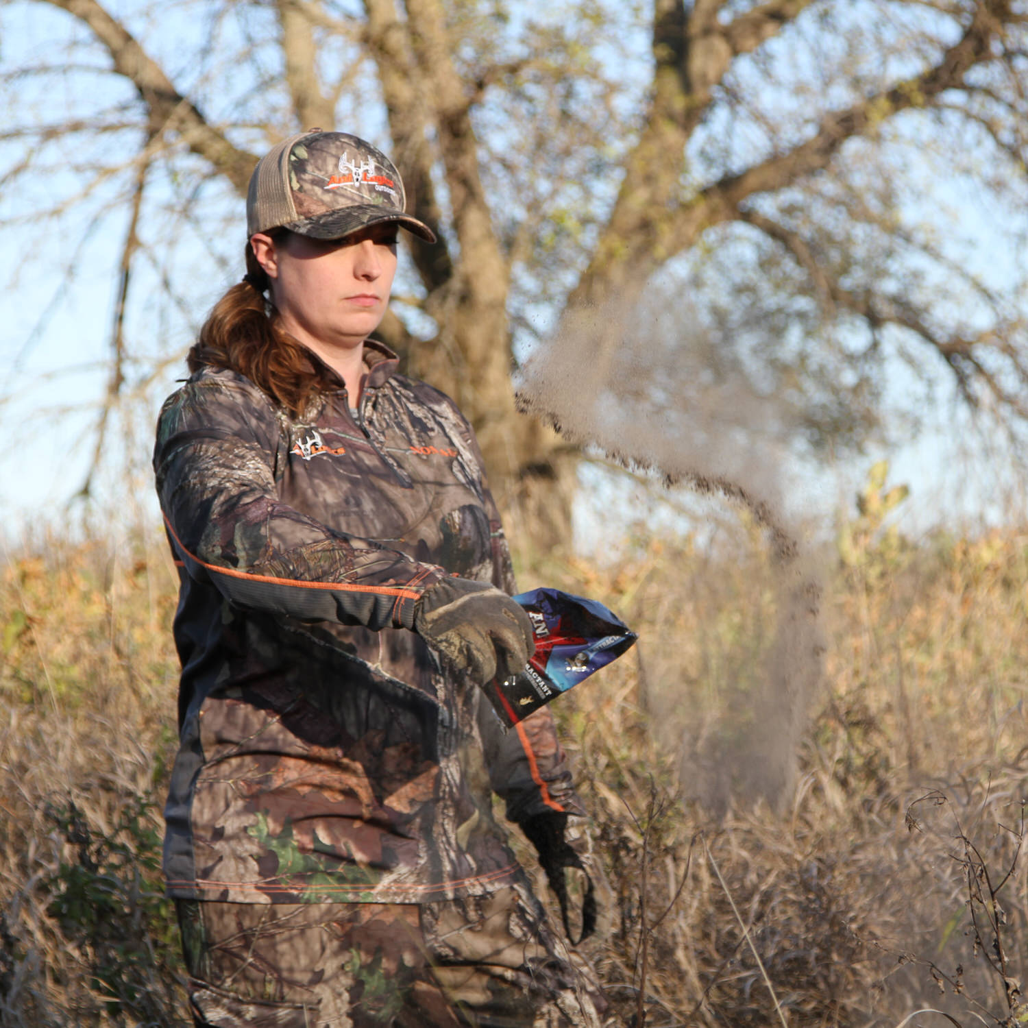 Woman spreading a bag of Ani-X Scent Attractant in the woods