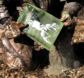 Man pouring a bag of Black Ops Deer Anthem Molasses Granular Attractant onto the ground