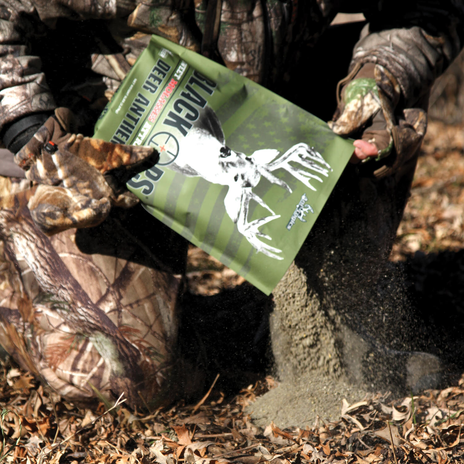 Man pouring a bag of Black Ops Deer Anthem Molasses Granular Attractant onto the ground