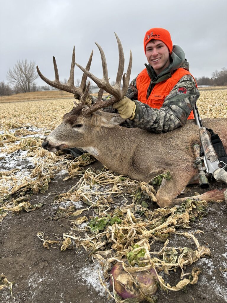 Man posing with a buck during winter in a food plot planted with the Perfect 10